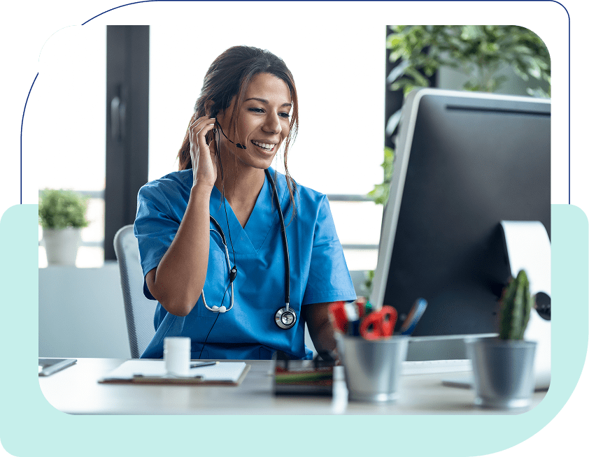 Smiling nurse on headset at computer desk.