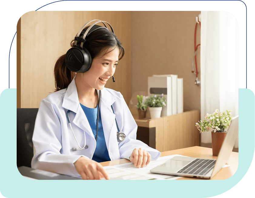 Female doctor wearing headphones and smiling at a laptop.